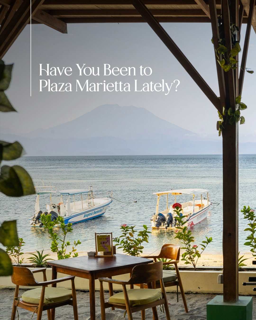 A table for two looking across the water to Mount Agung, outrigger boats moored in front