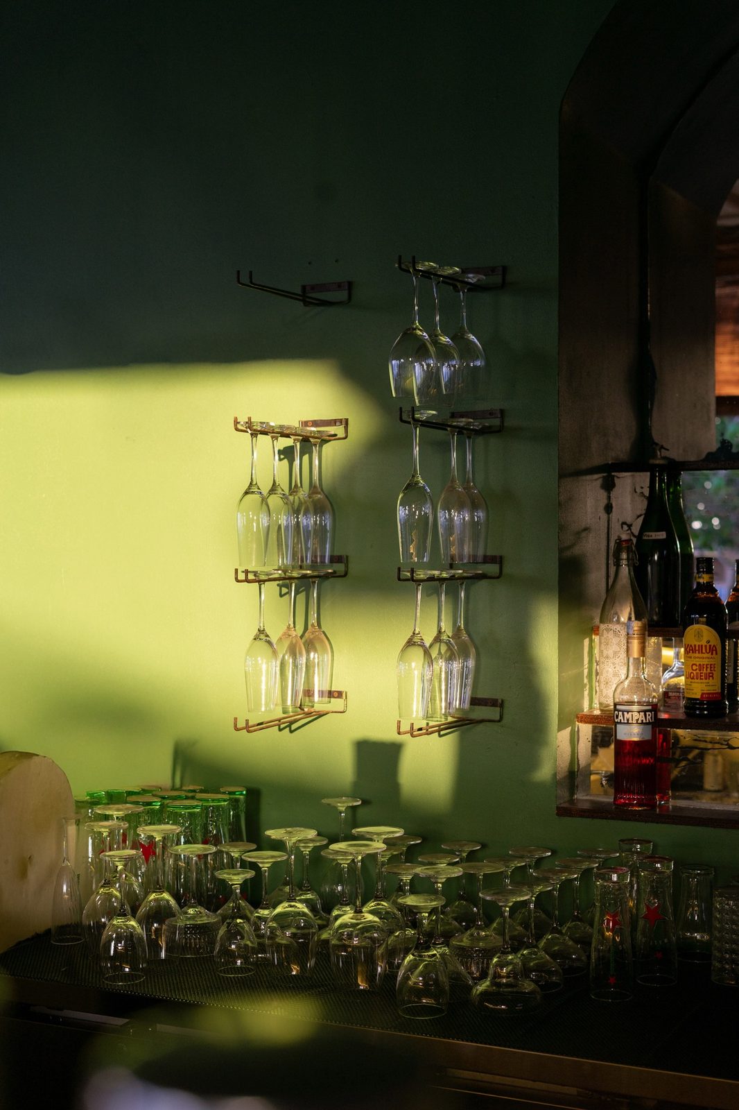 Glassware racks on the green bar wall in late afternoon light